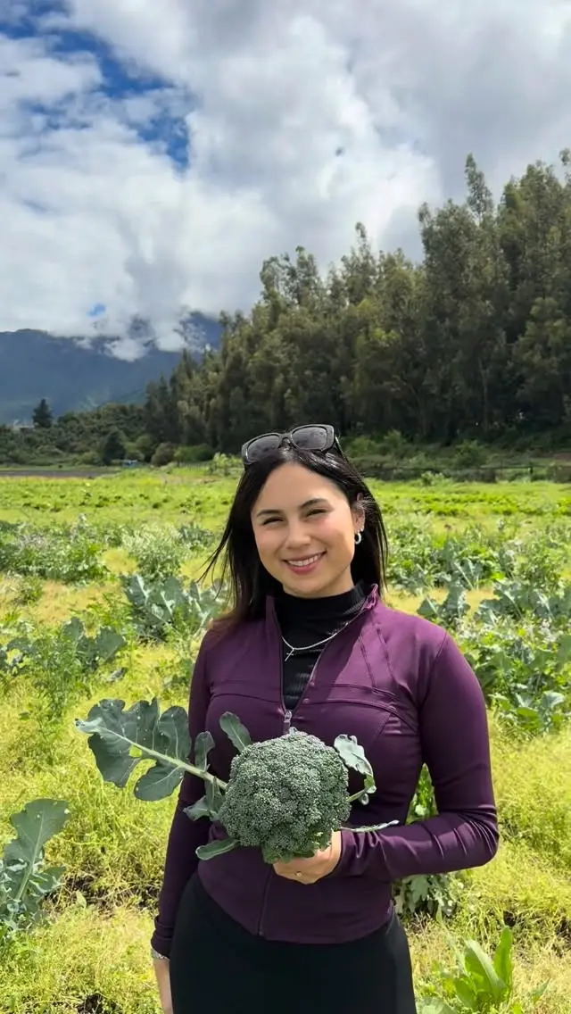 Fran en el campo sosteniendo un brócoli recién cosechado